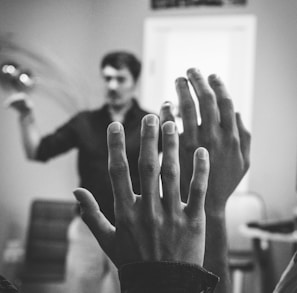 grayscale photography of two people raising their hands