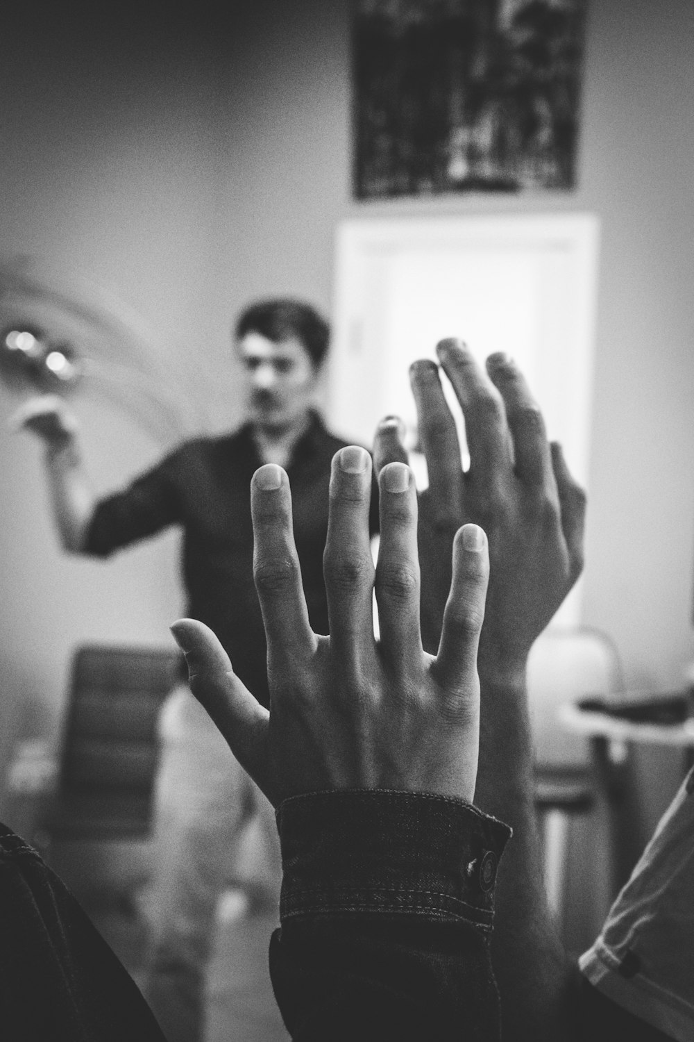 grayscale photography of two people raising their hands