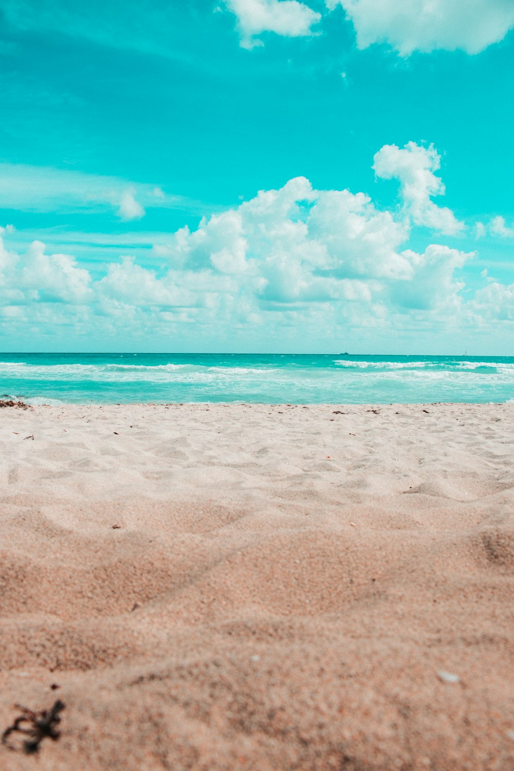 Strand unter blauem Himmel und weißen Wolken während des Tages