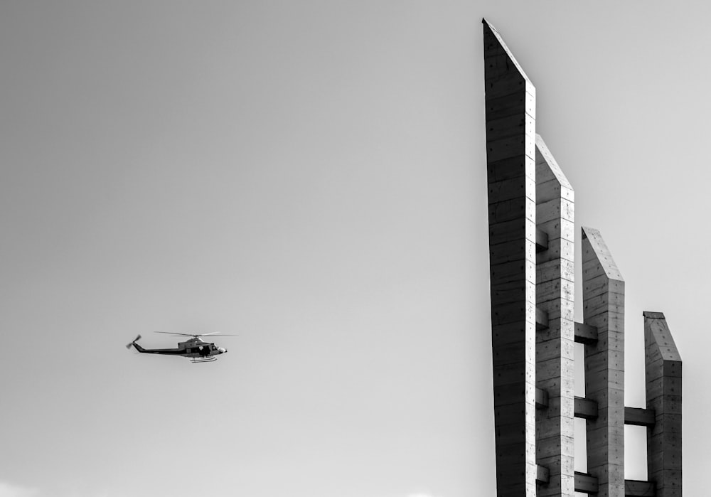 grayscale photography of helicopter near the building