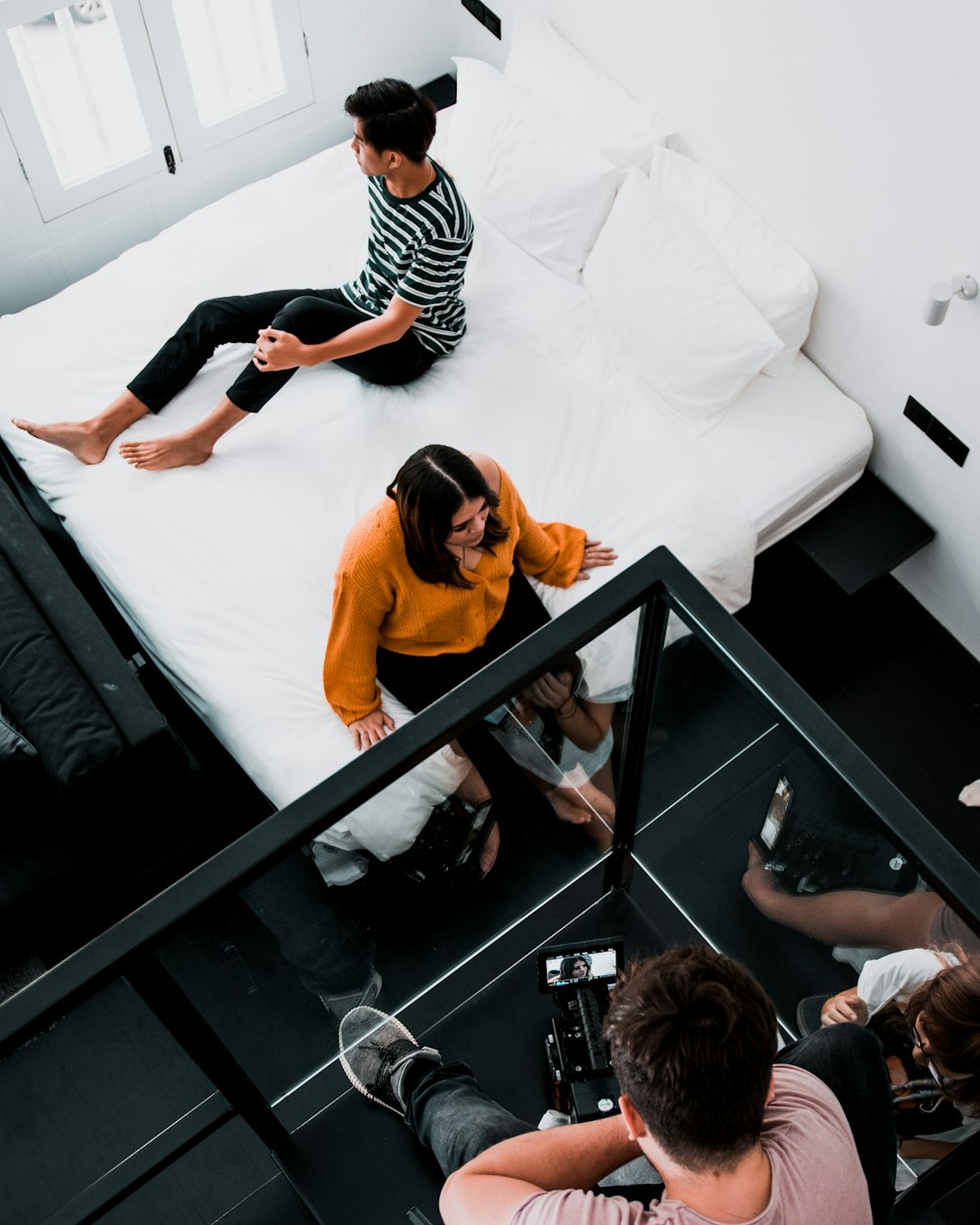 woman sitting on bed near man wearing white and black striped shirt