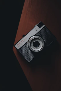 A moody black and white photo of a vintage camera on a dark textured surface