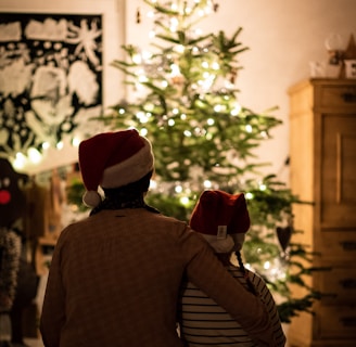 selective focus photography of girl an woman hugging each other in front of christmas tree