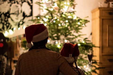 selective focus photography of girl an woman hugging each other in front of christmas tree