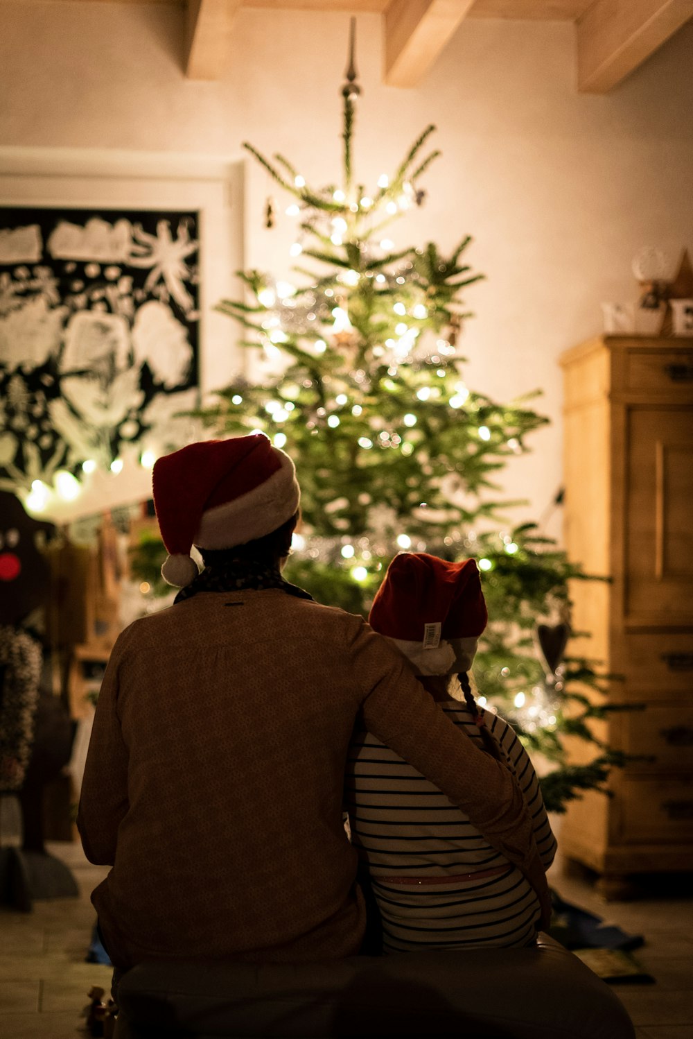 Fotografía de enfoque selectivo de una niña una mujer abrazándose frente al árbol de Navidad