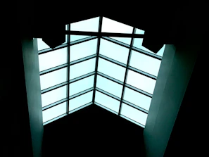 A sleek skylight replacement glowing softly with natural light filtering through, framed by dark roofing.