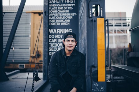 A man sitting under a warning sign.