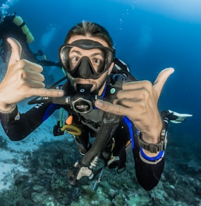 man underwater making hand signs