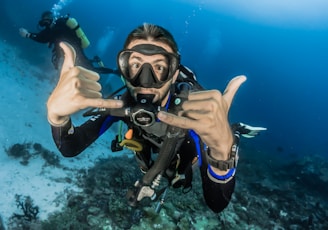 man underwater making hand signs