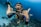 man underwater making hand signs