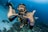 man underwater making hand signs
