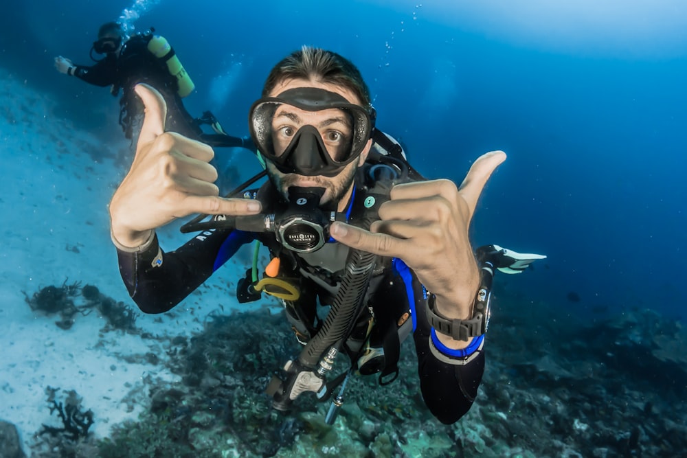 homme sous l’eau faisant des signes de la main