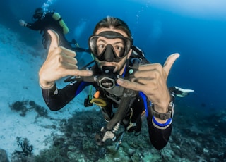 man underwater making hand signs