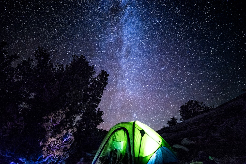 lights inside closed green and blue tent under starry sky