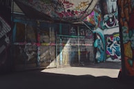 An urban alleyway with colorful graffiti and textured walls.