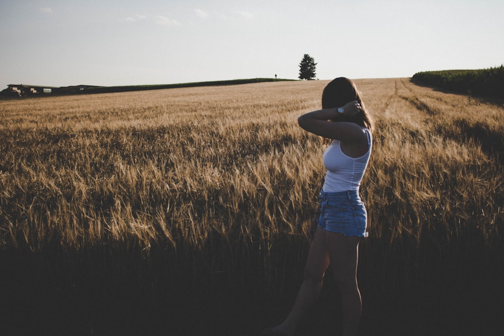 girl in white tank top posing near brown field