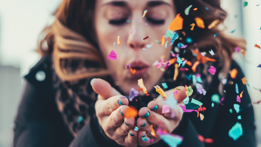 woman blowing paper strips in selective focus photography