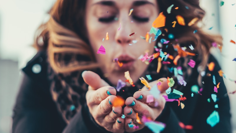 Guest blowing a handful of colorful confetti toward the camera