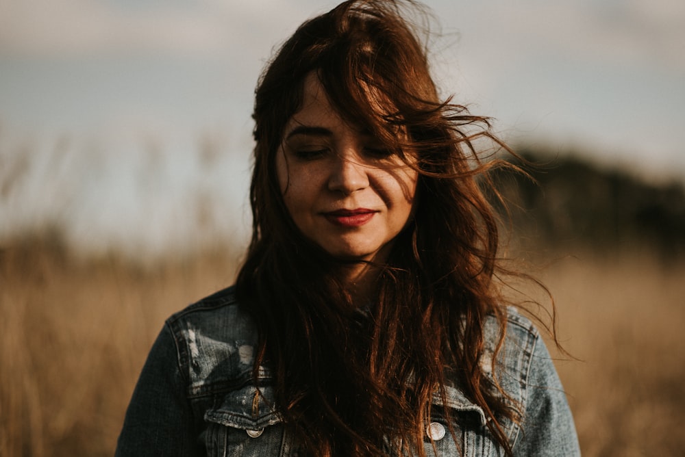 Selektive Fokusfotografie einer lächelnden Frau, die von einem Weizenfeld umgeben ist