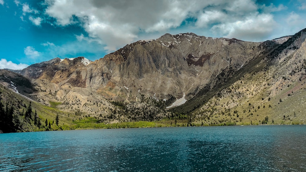 Specchio d'acqua vicino alla montagna grigia sotto il cielo blu