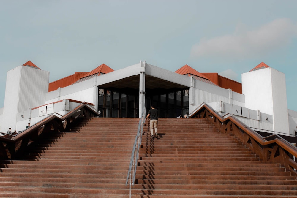 person on stair near white and orange building