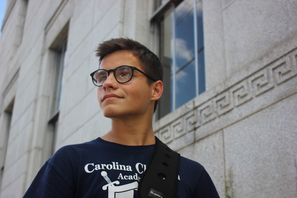 man wearing eyeglasses standing near building during daytime