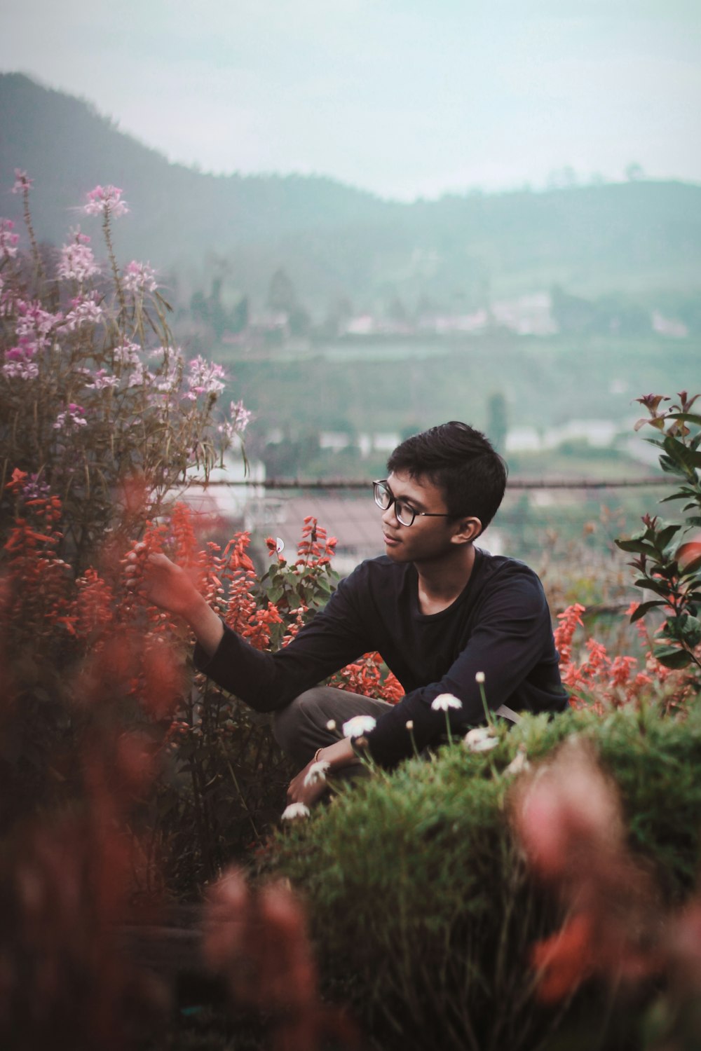 man in black long-sleeved shirt touching flowers during daytime