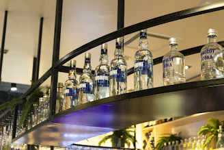 Close-up of premium beverage bottles arranged elegantly on a minimalist shelf under cool lighting.