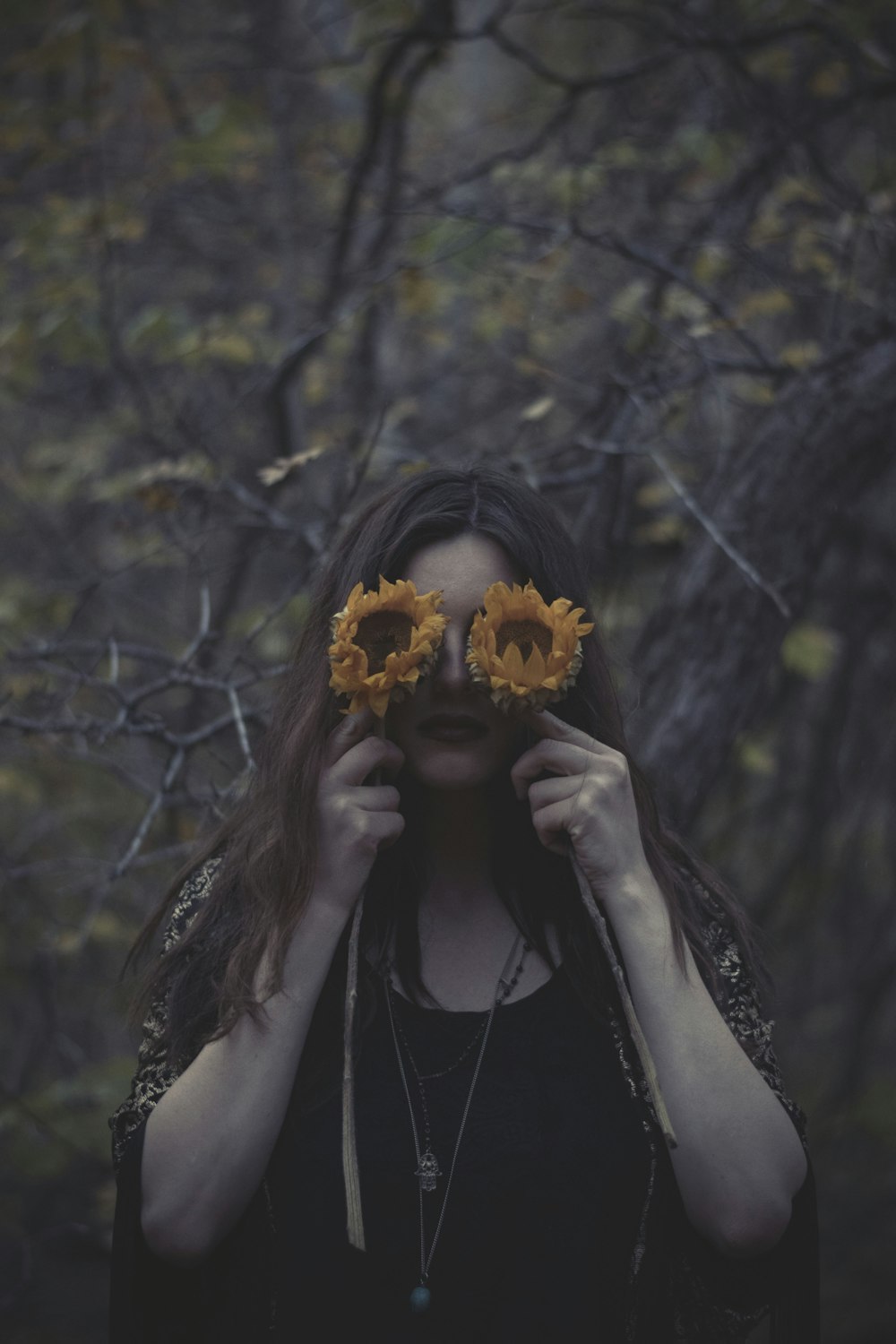 woman covering her eyes using sunflowers
