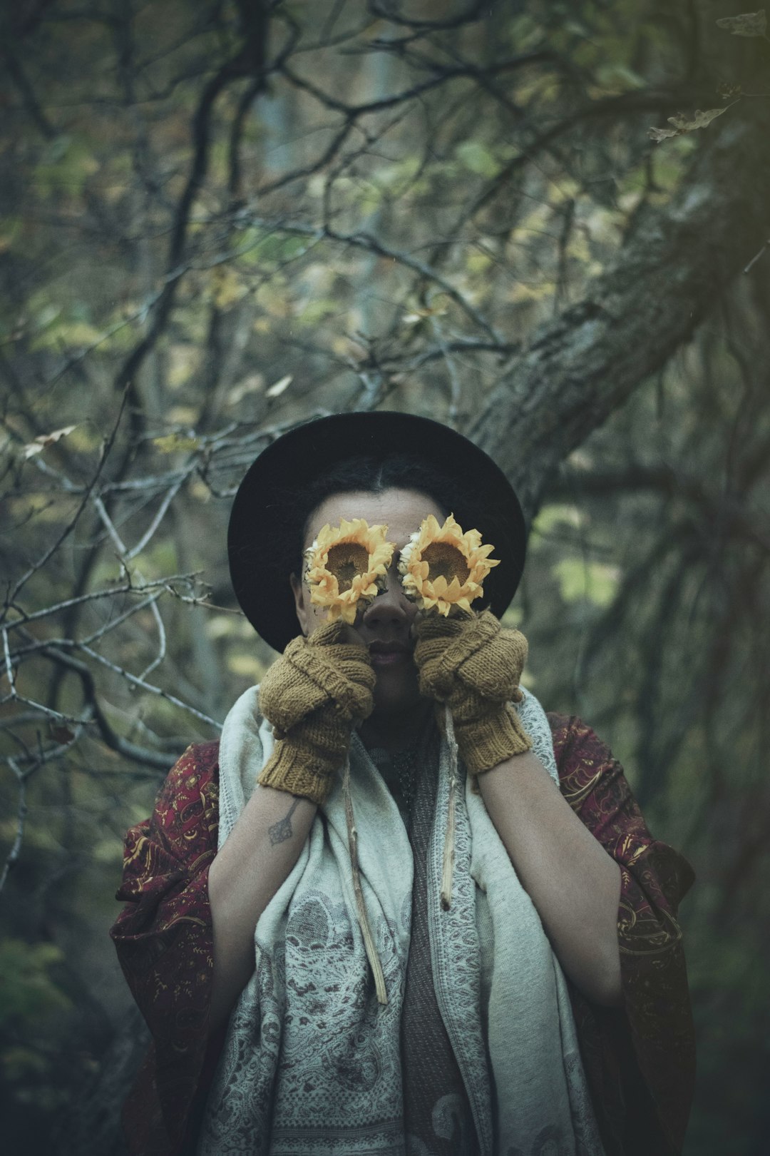 person covering eyes with sunflowers