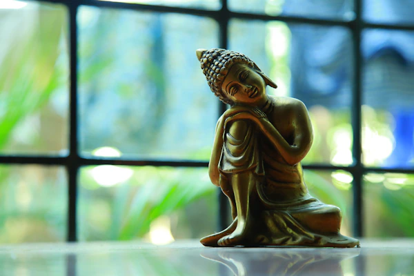 A serene meditation sculpture resting on a smooth charcoal surface with bronze accents.