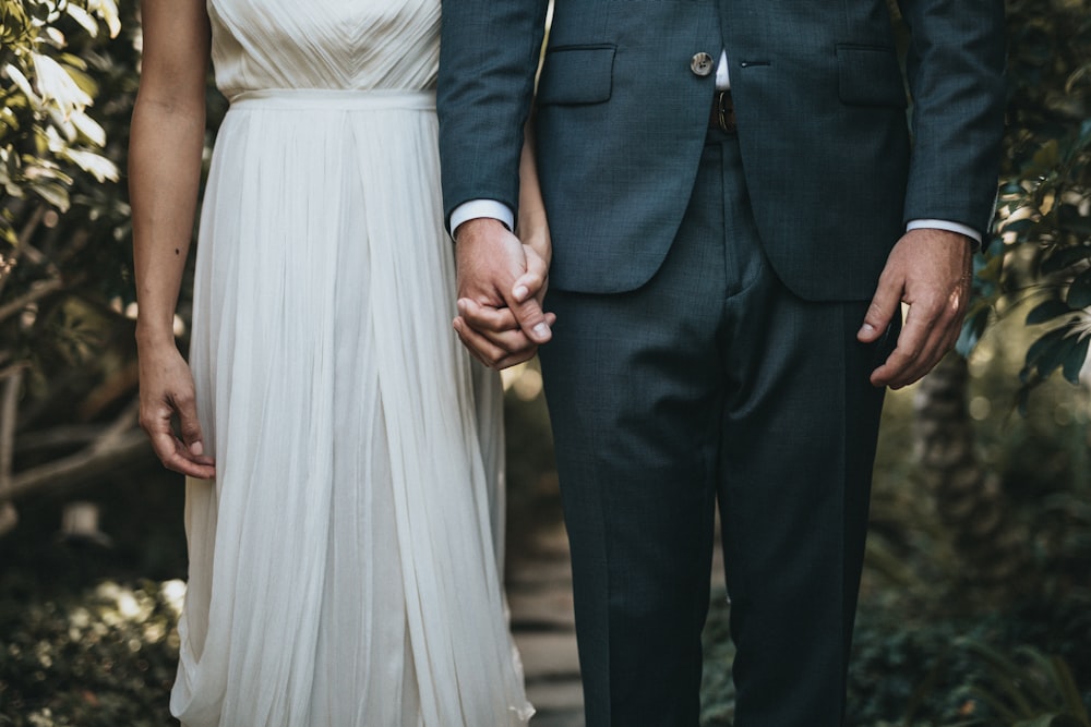 man in formal suit and woman in gray dress holding hands