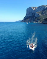 A group of friends laughing together while boating on crystal-clear waters under a sunny blue sky.