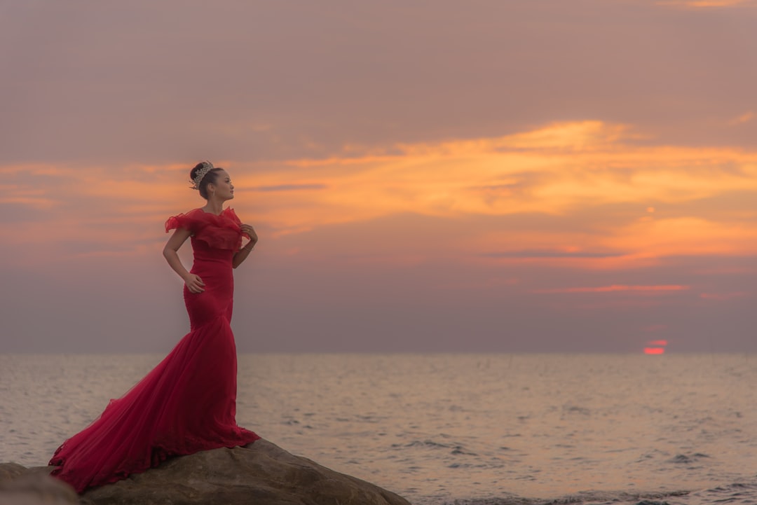 woman in red dress near body of water