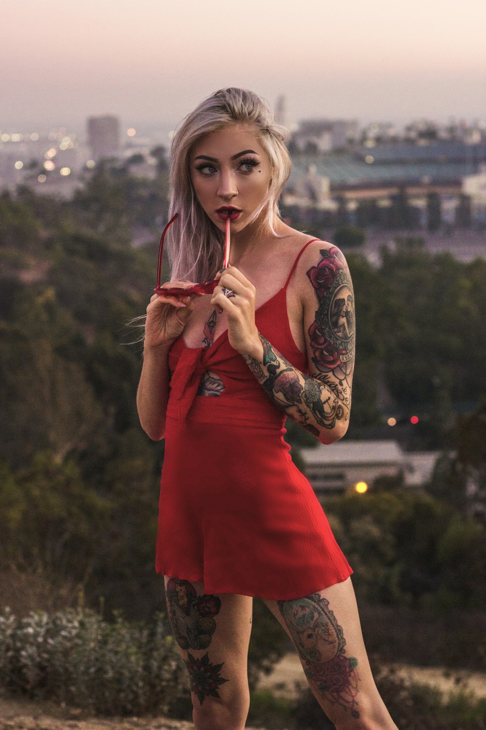 standing woman in red dress biting glasses