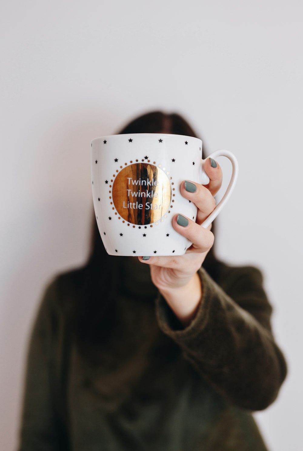 woman holding mug covering her face