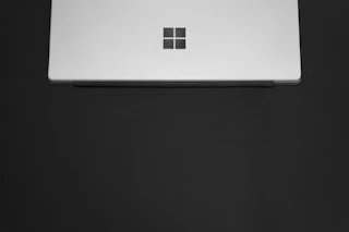 A sleek, minimalistic web design layout on a laptop screen with black, white, and gold accents.