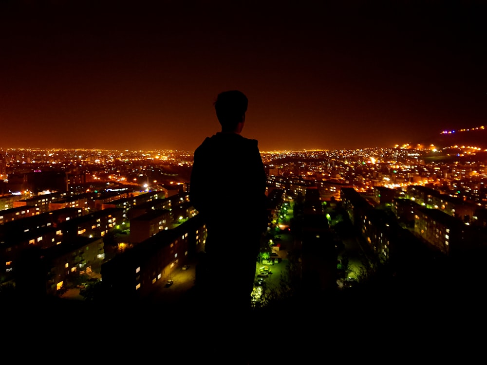 silhouette photo of person facing on lighted city