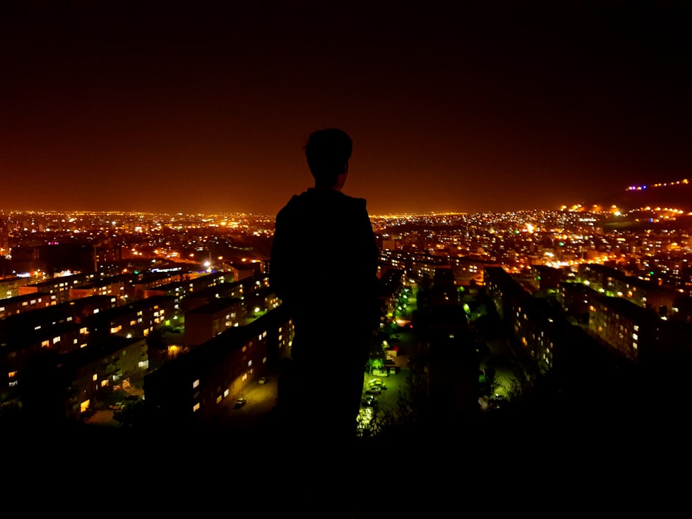 photo de silhouette d’une personne faisant face à une ville éclairée