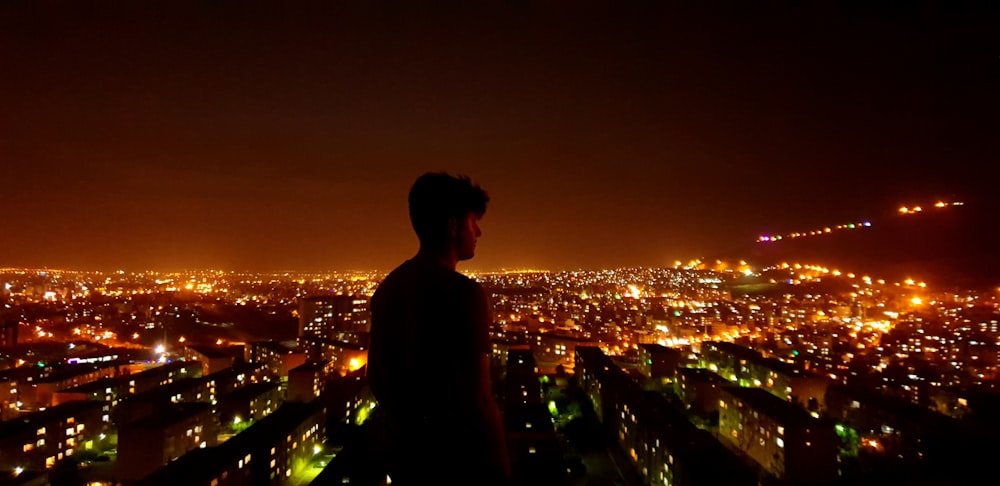 man standing looking at his right near city during night