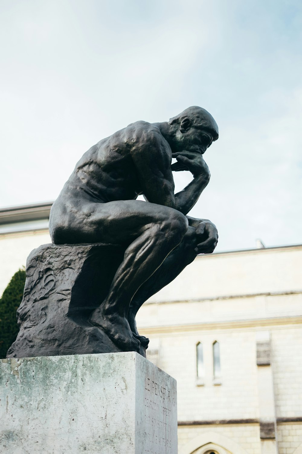 Una estatua de un hombre sentado encima de un bloque de cemento