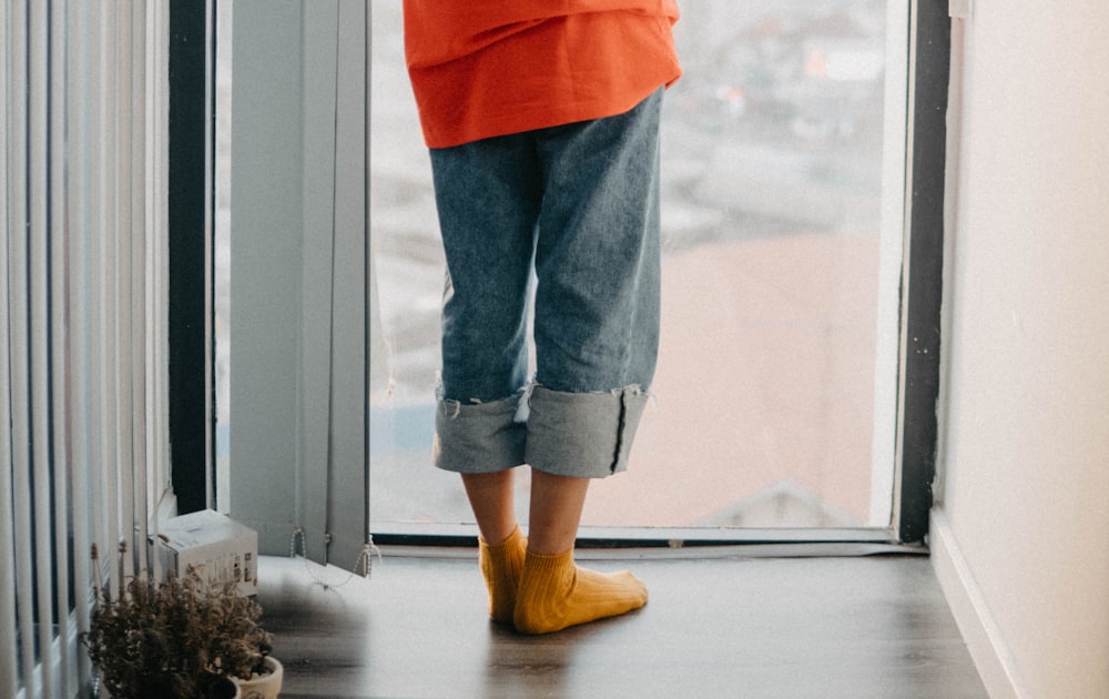 person wearing orange socks while standing near glass wall