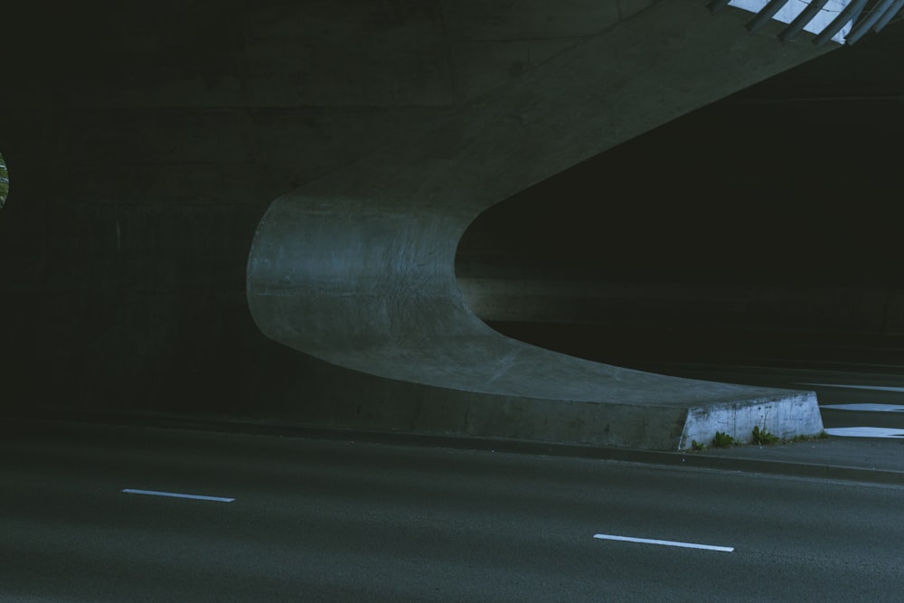 a man riding a skateboard down a street under a bridge