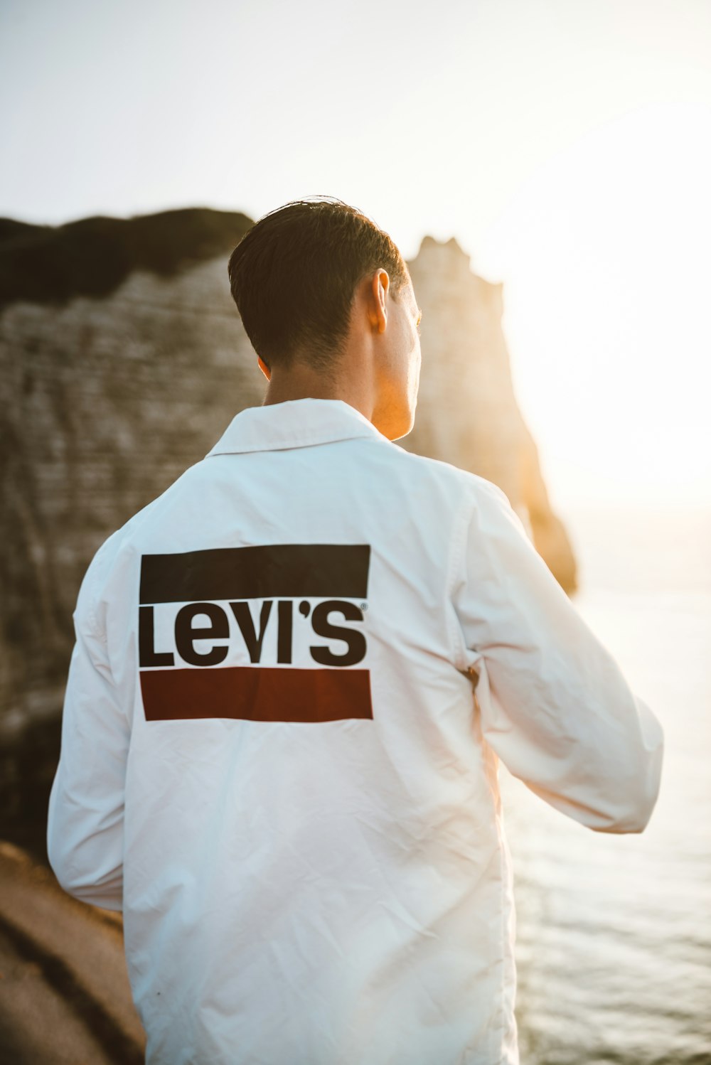 Mann in weißem Levi's-Hemd am Strand