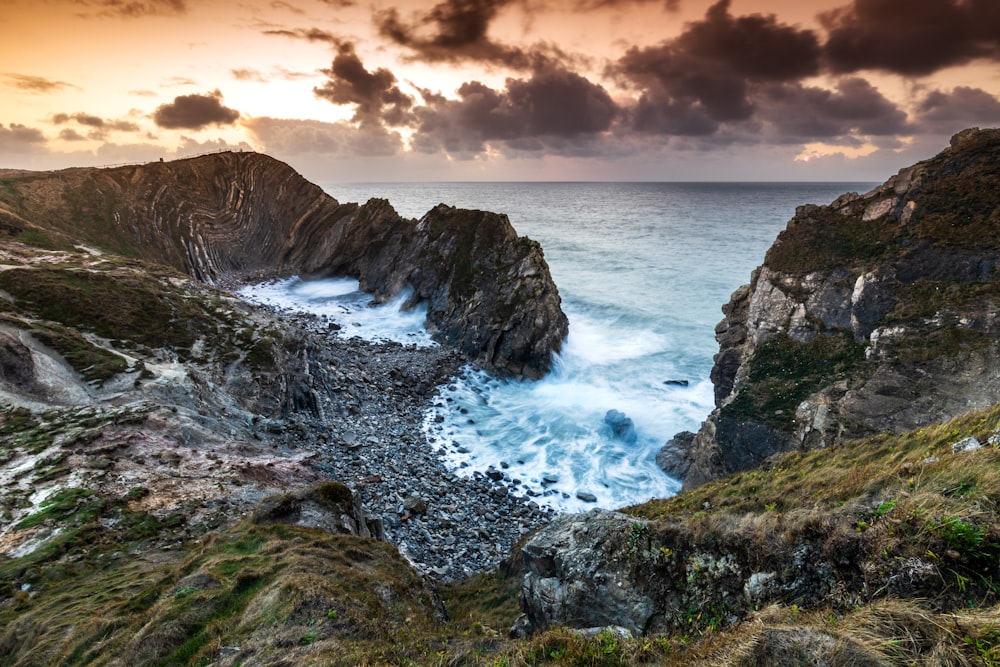 body of water beside cliff