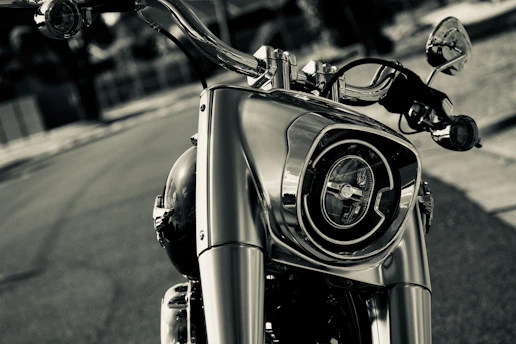Close-up of a sleek motorcycle headlight glowing with bright LED light against a dark urban background.