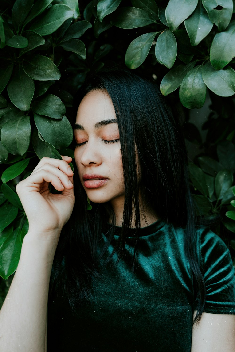 woman wearing green crew-neck shirt beside green-leafed plant