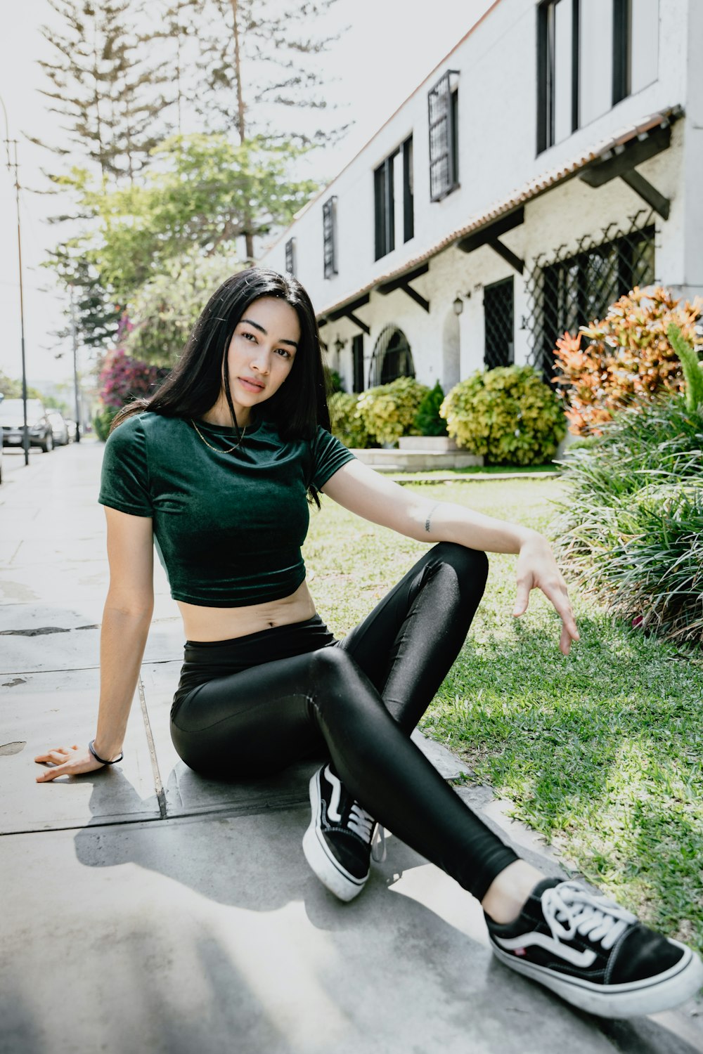 woman sitting on concrete ground beside grass lawn