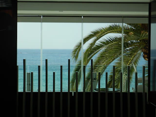 Close-up of hands signing a contract with a tropical sea view through the window.
