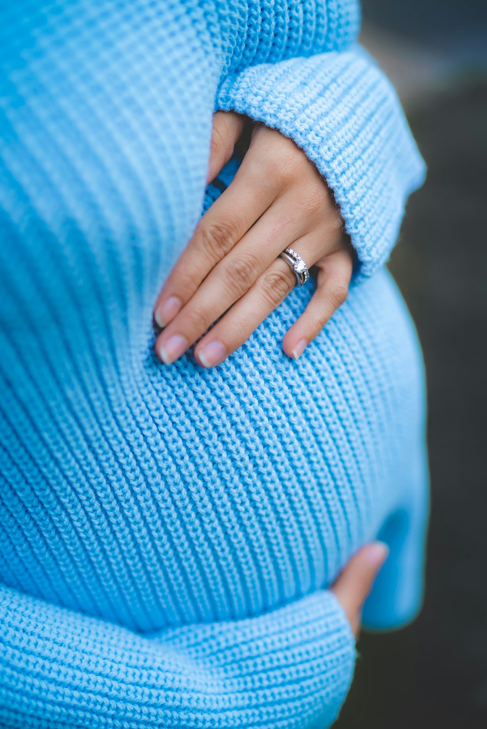 mujer sosteniendo su vientre mientras usa un suéter de punto azul